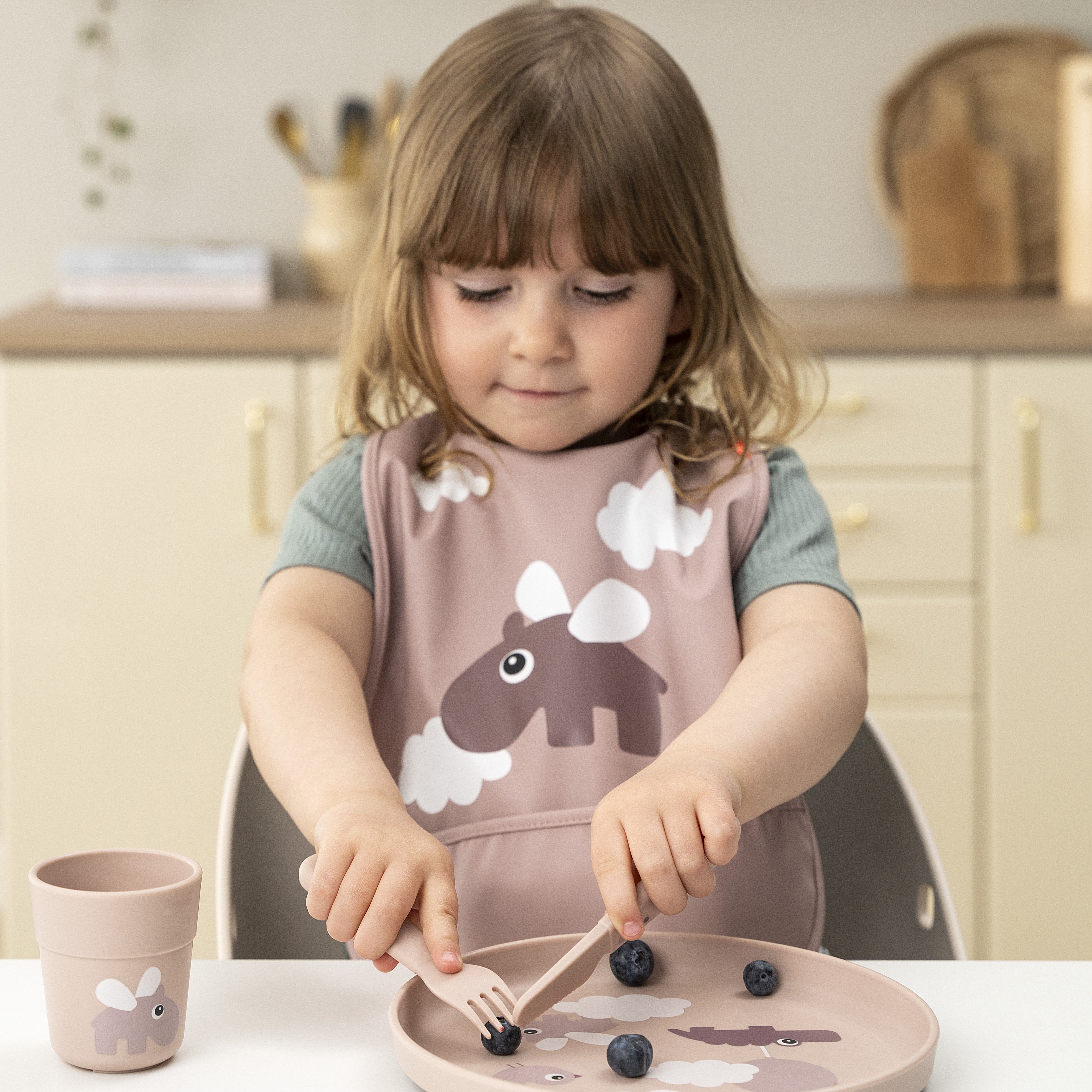 Girl wearing a powder Done by Deer pocket bib with Ozzo the hippo