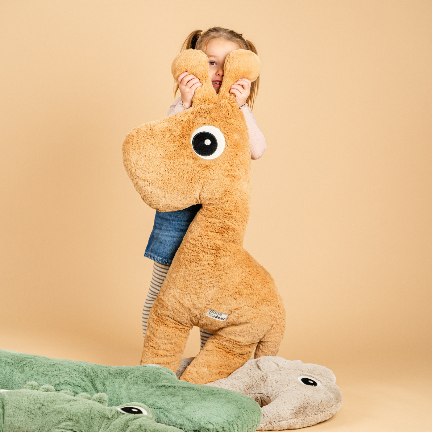 Girl hiding behind her big Raffi the giraffe cuddle toy