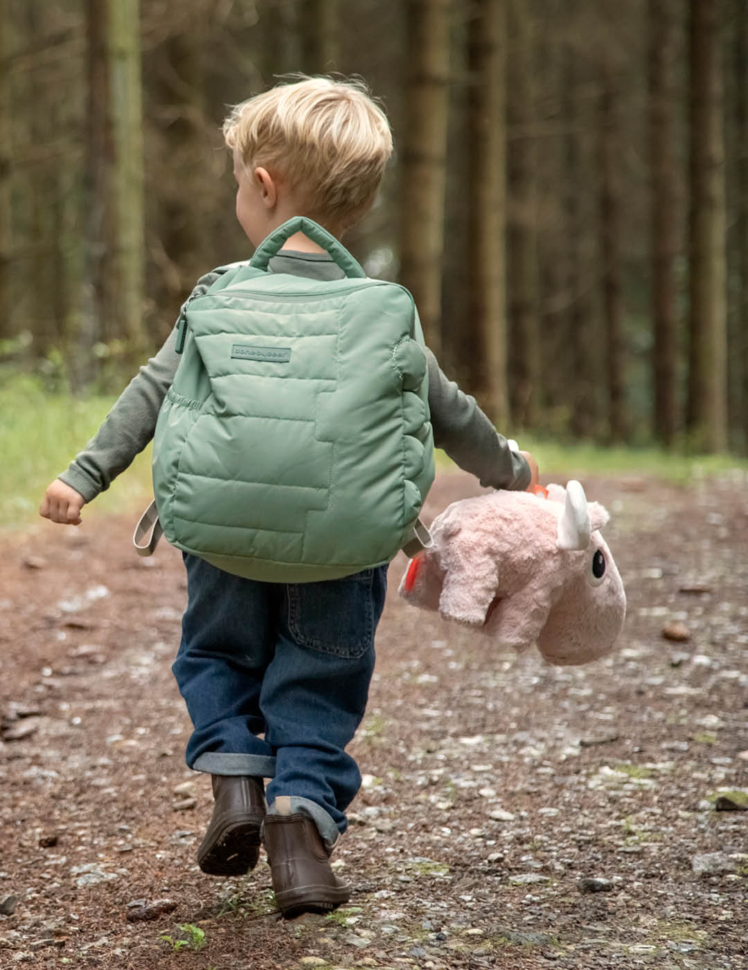 A boy with Done by Deer quilted kids backpack and an Ozzo cuddle toy