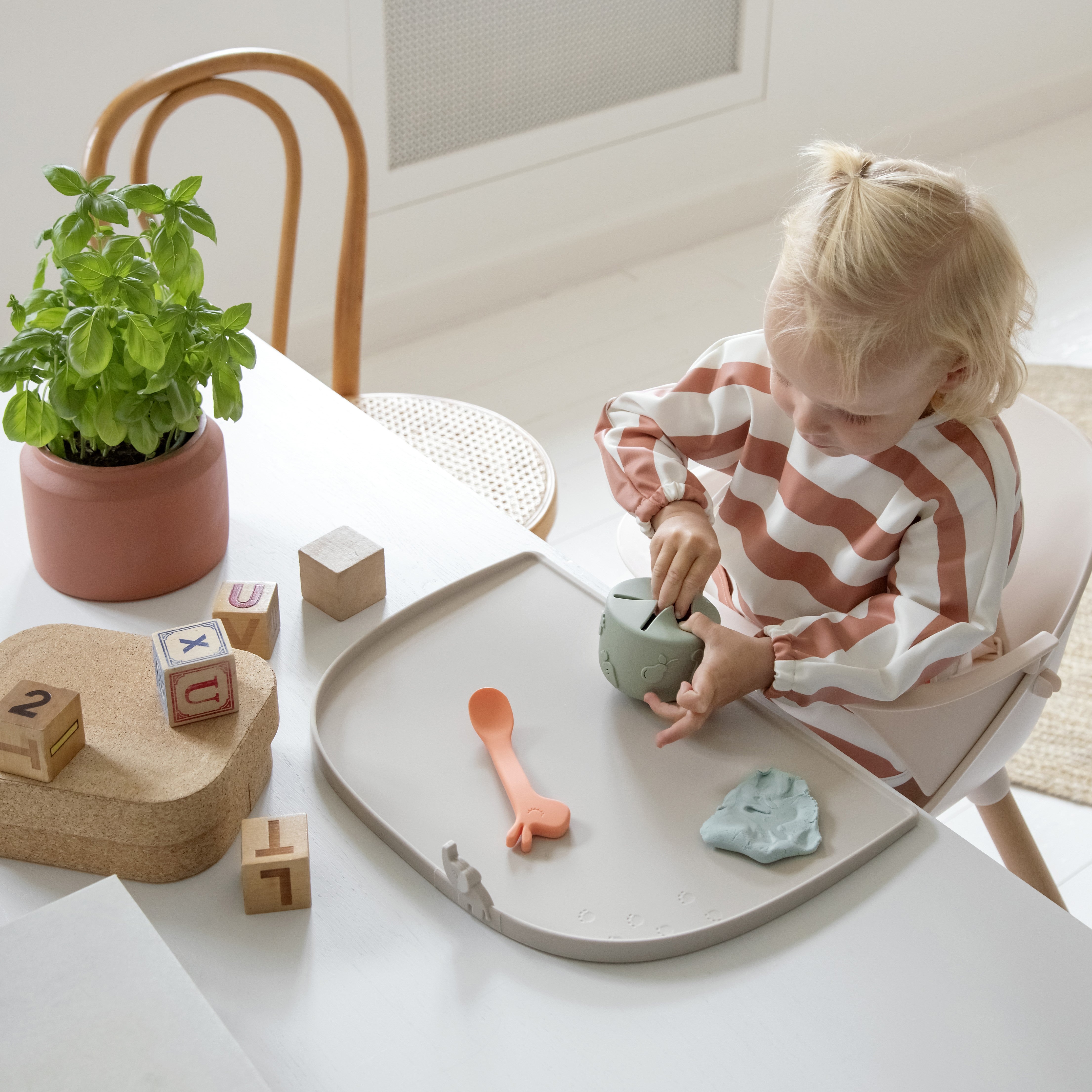 Girl eating from a Doe by Deerr snack cup using a high-edge placemat to catch falling food
