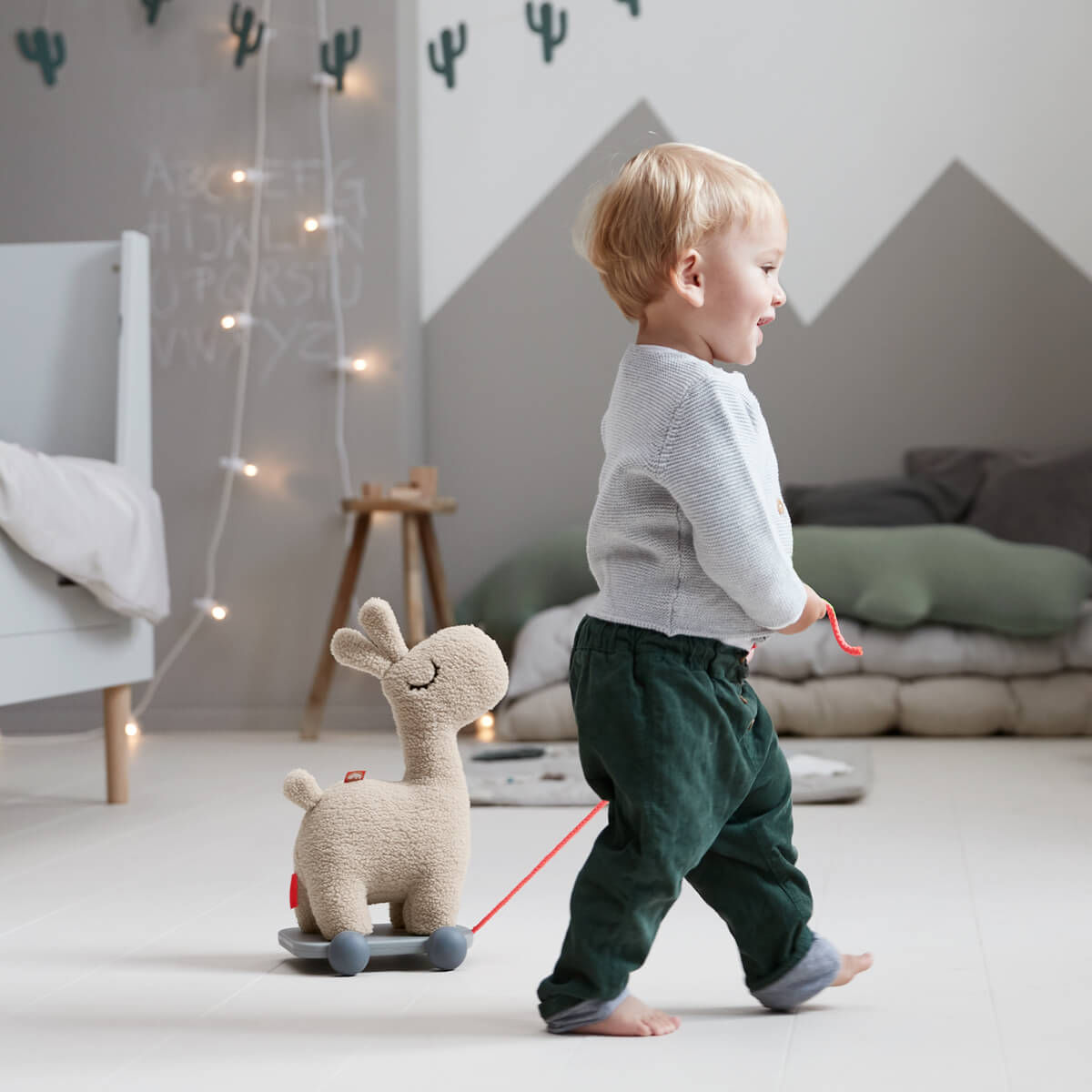 Kid with pull along toy Lalee Llama from Done by Deer in sand