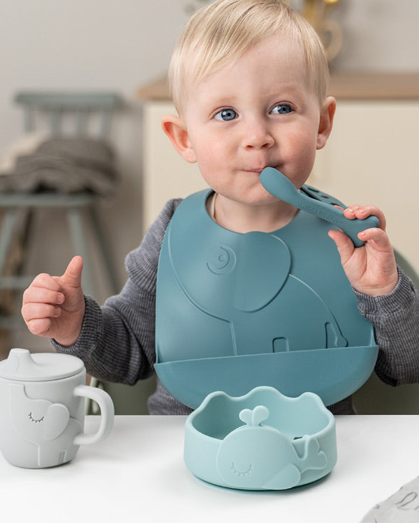 Boy learning to eat by himself using Done by Deer spoon and bowl