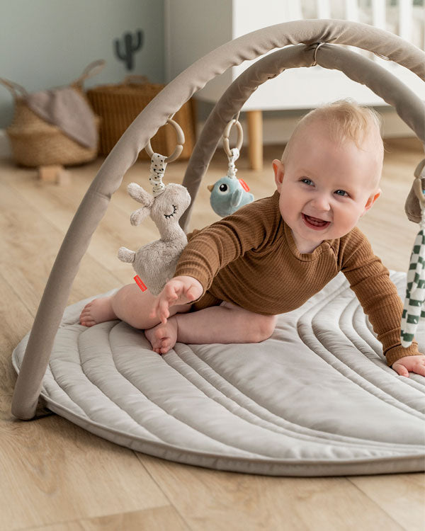 Baby playing in a Done by Deer activity play gym 