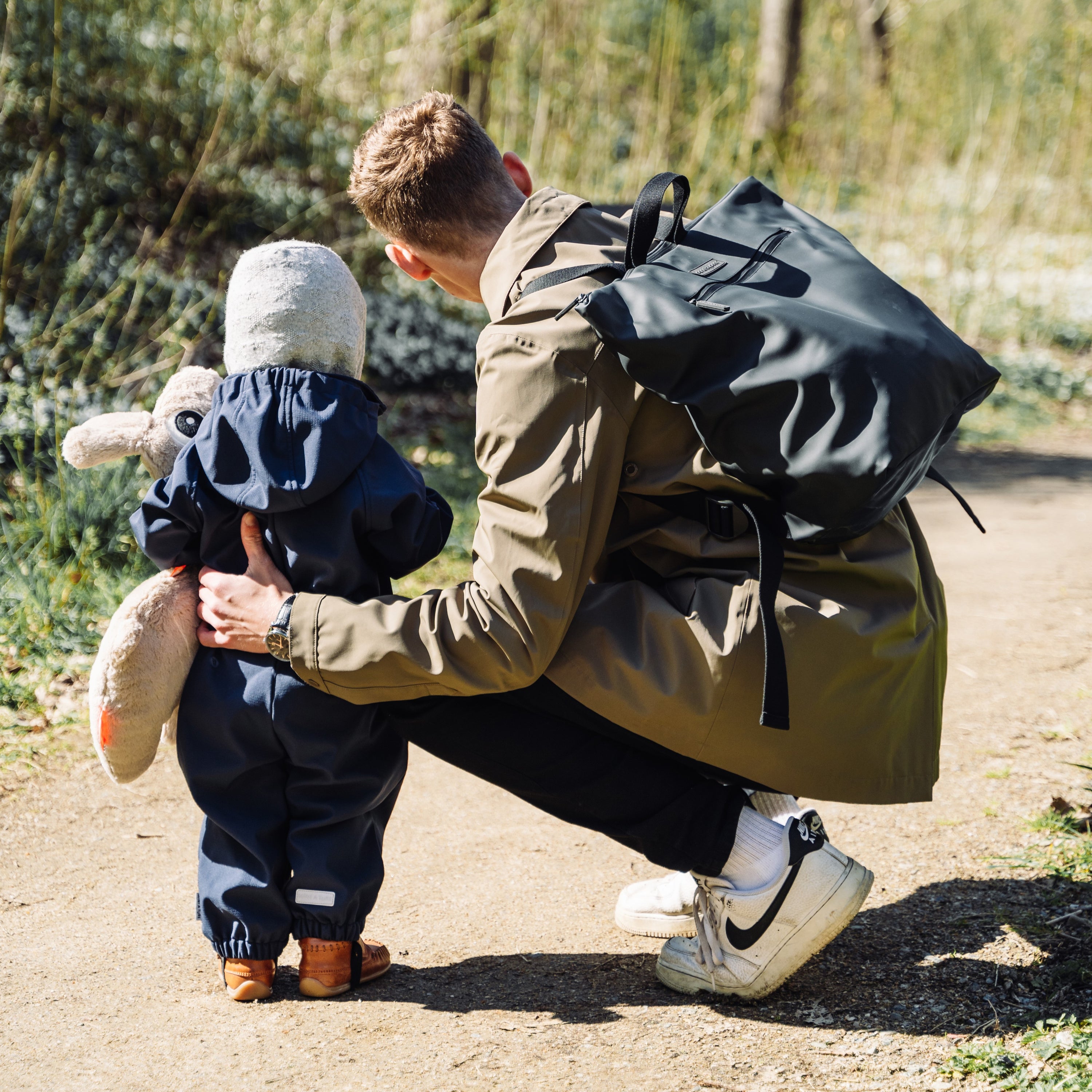 Man and child outside with a Done by Deer changing backpack