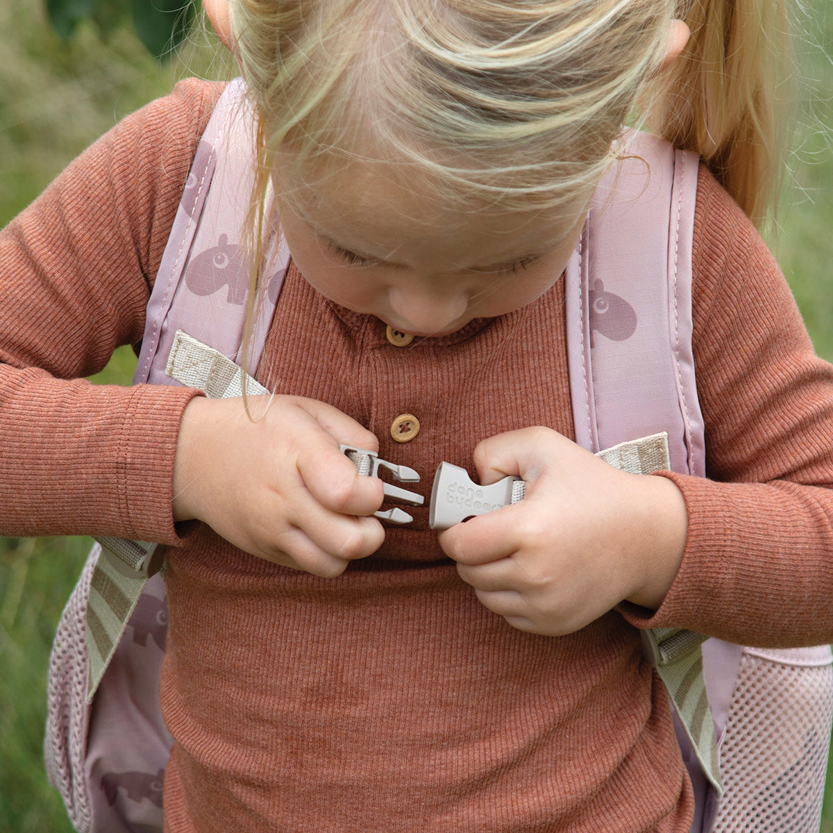 Girl putting on her Done by Deer Ozzo kids backpack.